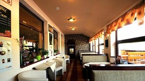 Un restaurante con cabinas y mesas, una barra y vista a la calle.