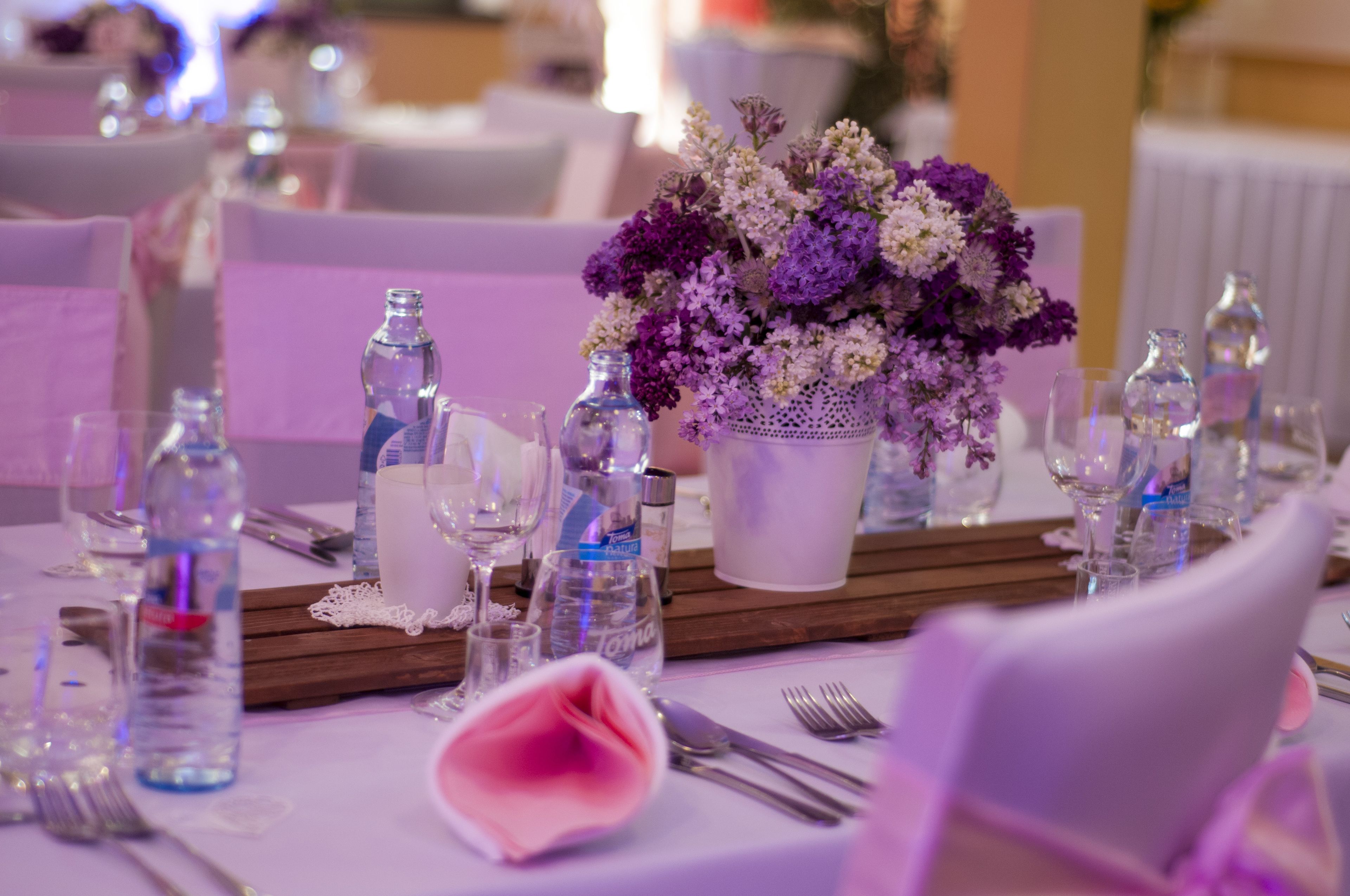 Una mesa dispuesta para un evento formal, con un centro de mesa floral, copas de cristal transparente y un camino de mesa blanco.