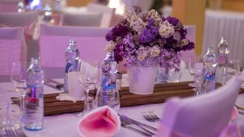 Una mesa dispuesta para un evento formal, con un centro de mesa floral, copas de cristal transparente y un camino de mesa blanco.