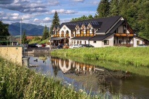 A traditional building with a balcony, solar panels, and a reflection in the water. - Penzion Zivka (Zavazna Poruba)