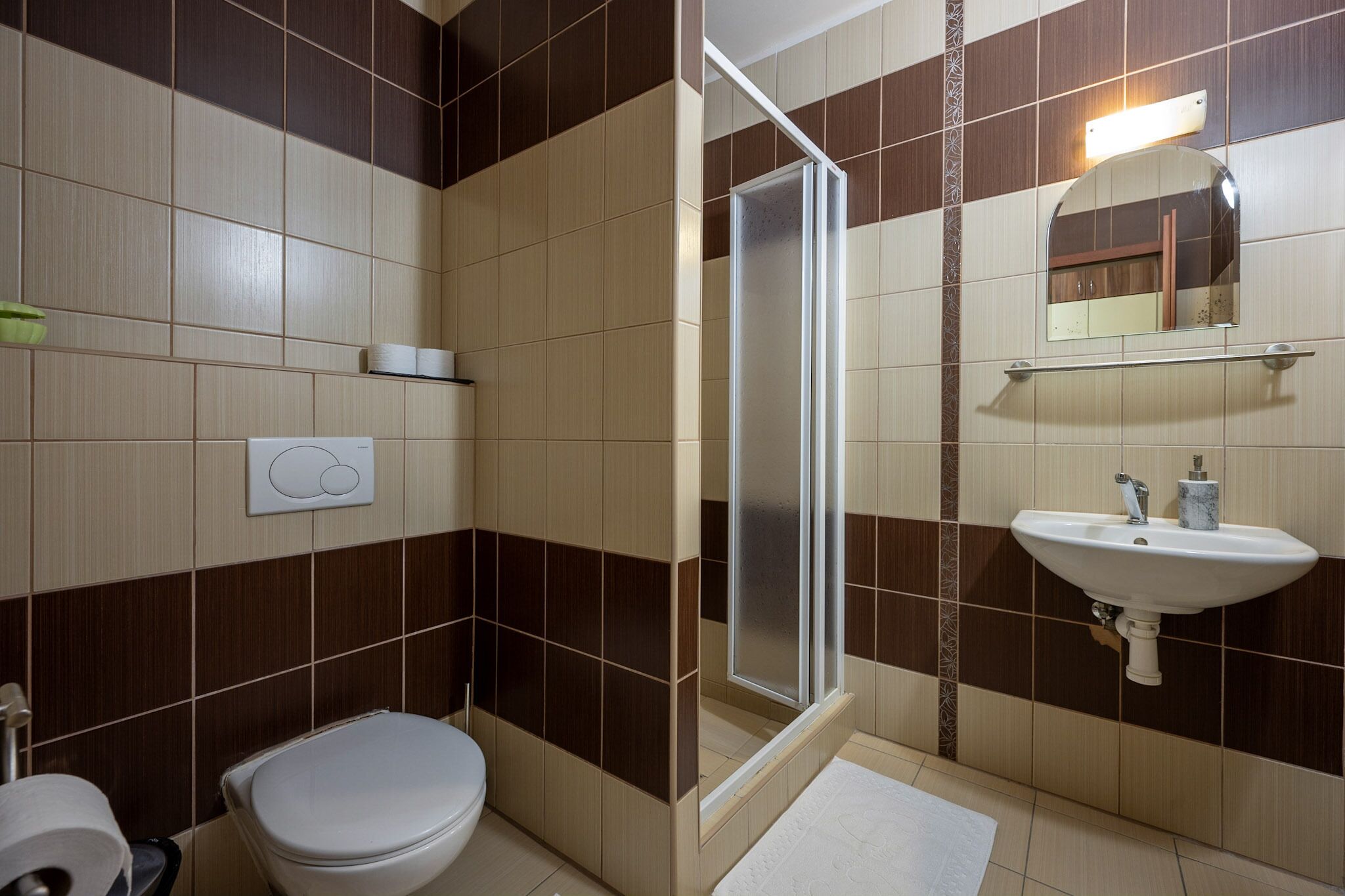 A bathroom with a toilet, a shower, and a sink.