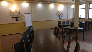 A conference room with a long table and chairs, a whiteboard, and wall-mounted light fixtures.