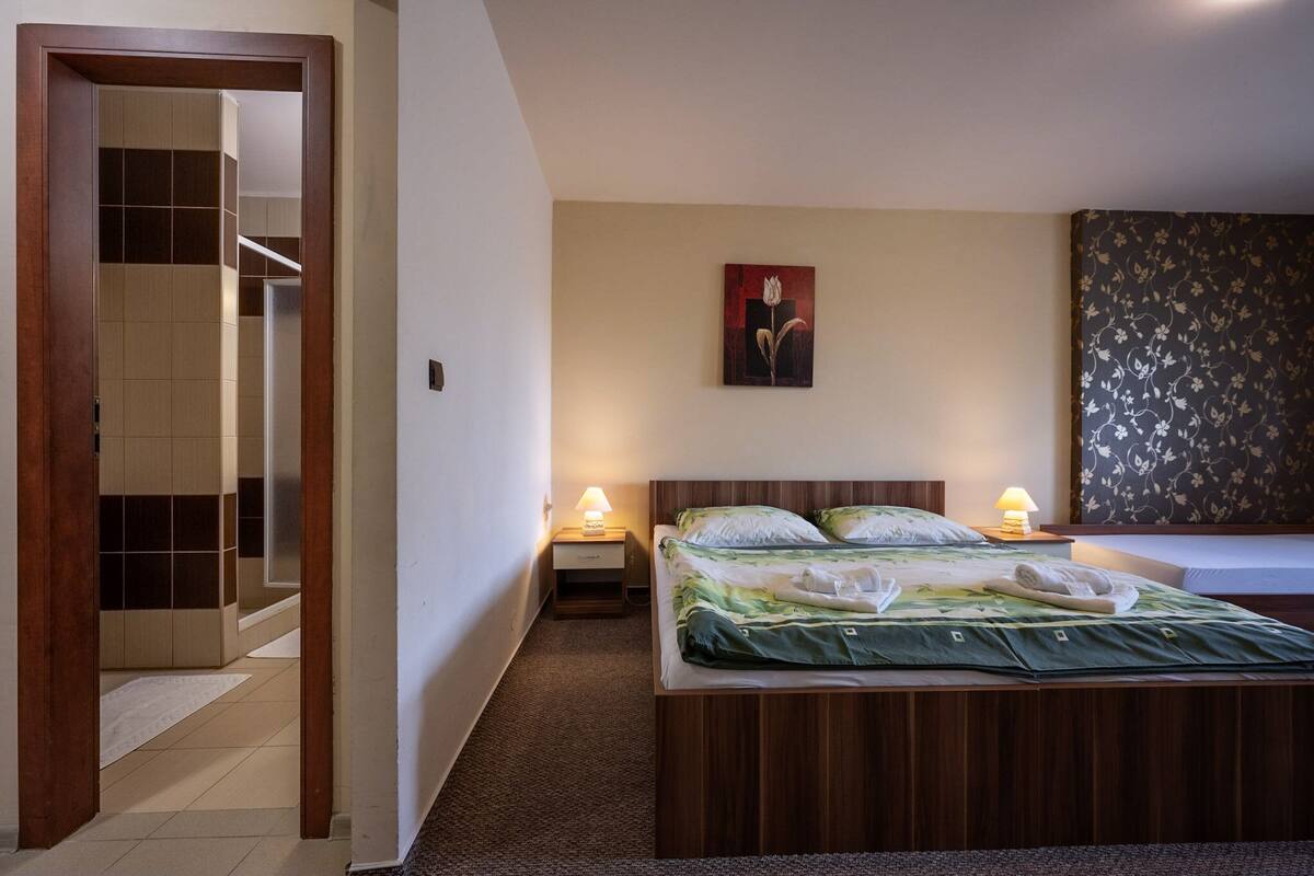Une chambre d’hôtel avec un lit, des lampes de chevet, un tableau et un mur décoré d’un motif.