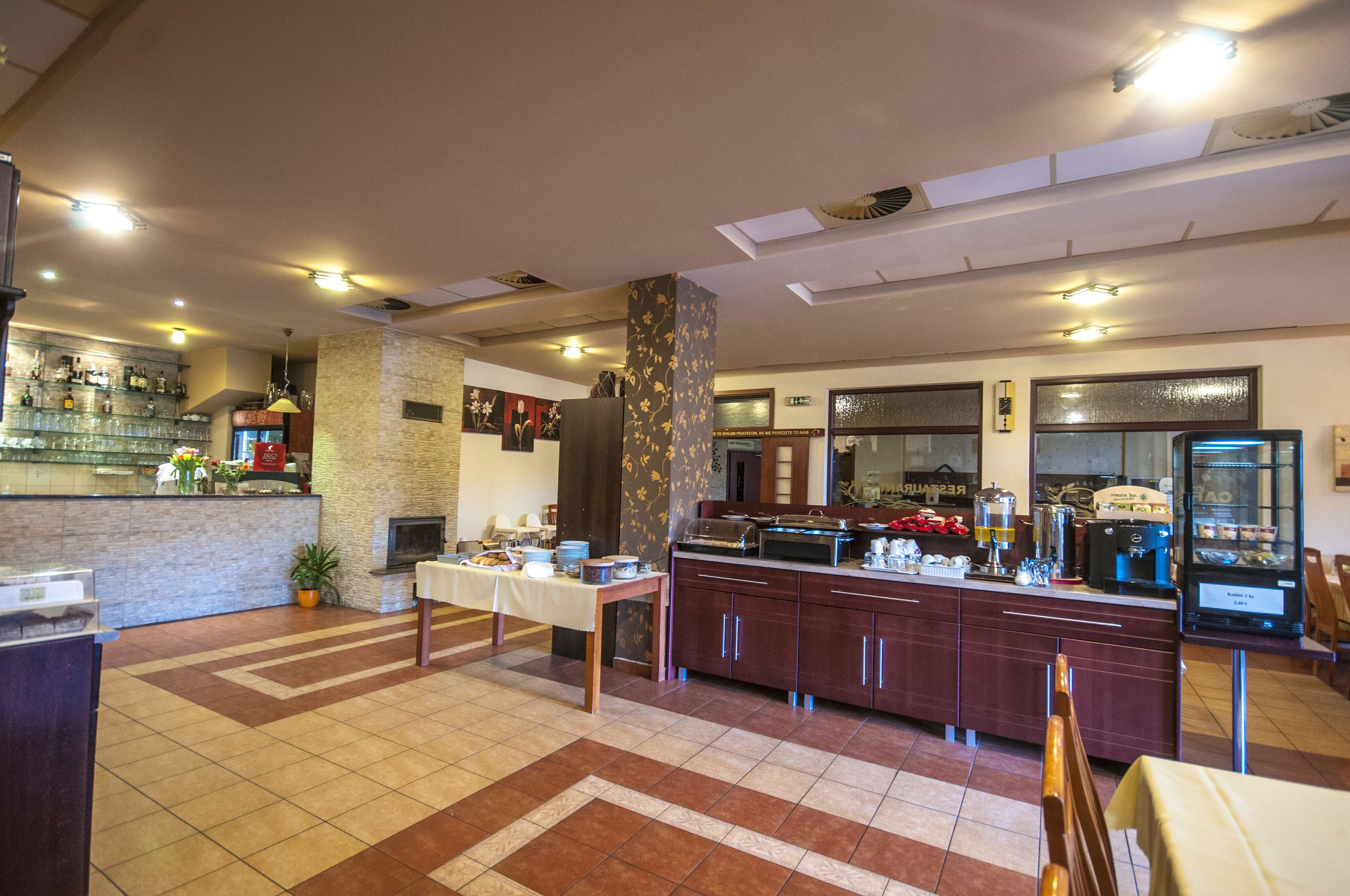 Um saguão de hotel com balcão de recepção, espaço para buffet e área de estar.