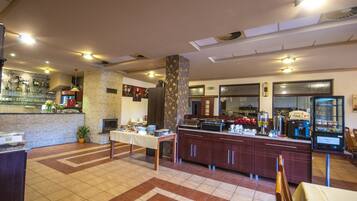 Um saguão de hotel com balcão de recepção, espaço para buffet e área de estar.