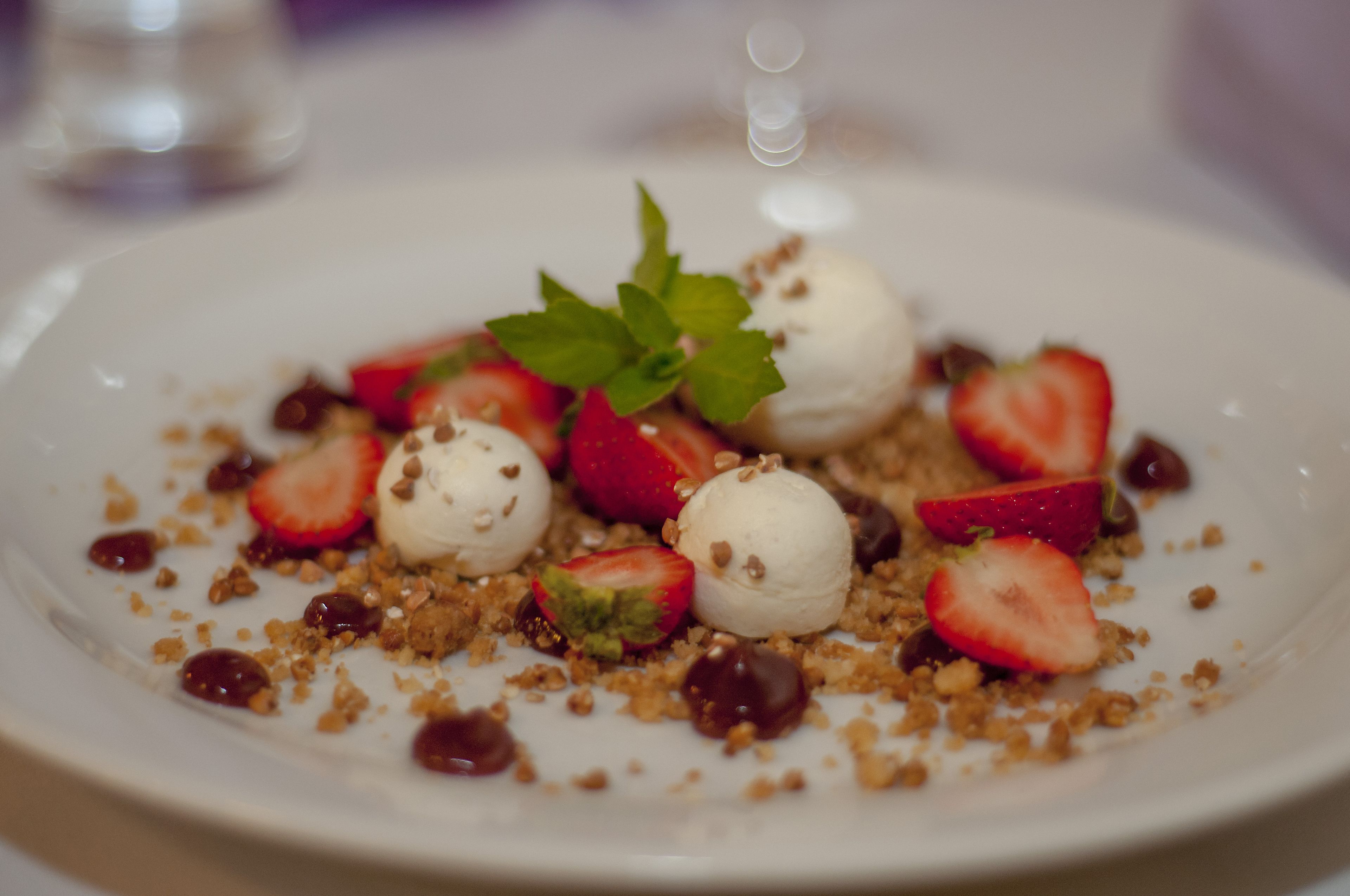 A dessert plate with strawberries, ice cream, and granola.
