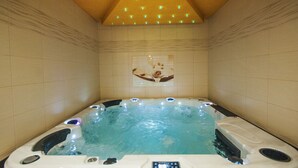 Un jacuzzi con panel de control, rodeado de paredes de baldosas color beige y techo de madera.