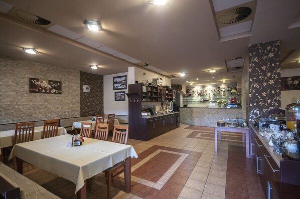 A restaurant with a bar area, dining tables, and a kitchen counter. - Penzion Zivka (Zavazna Poruba)
