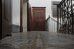 Um corredor com piso estampado que leva a uma porta de madeira.