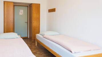 Una habitación con dos camas individuales, piso de madera y una puerta con un letrero.