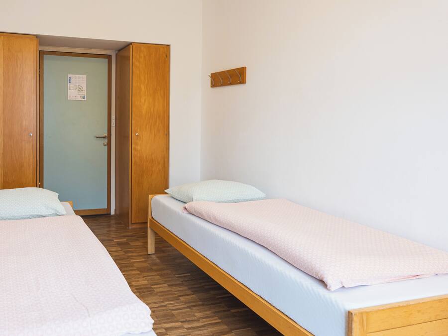 Una habitación con dos camas individuales, piso de madera y una puerta con un letrero.