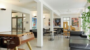 A modern lobby with a foosball table, a sofa, and a dining area with chairs and tables. - Youth Hostel Richterswil (Richterswil)