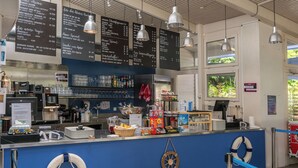 A restaurant counter with a blue backdrop, menu boards, and various food items displayed. - Youth Hostel Richterswil (Richterswil)