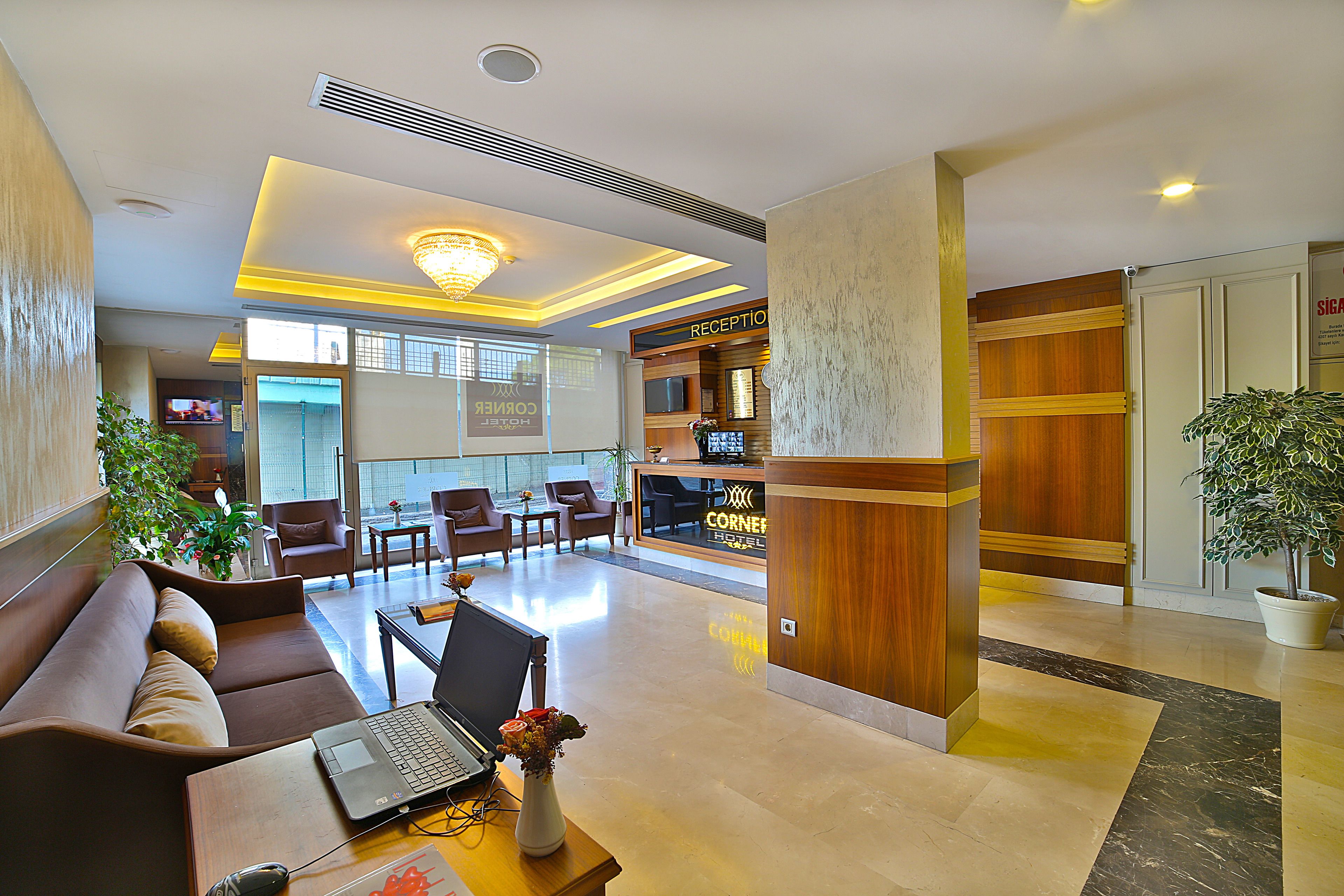 Een hotel lobby met een receptiebalie, een zithoek en een groot raam.