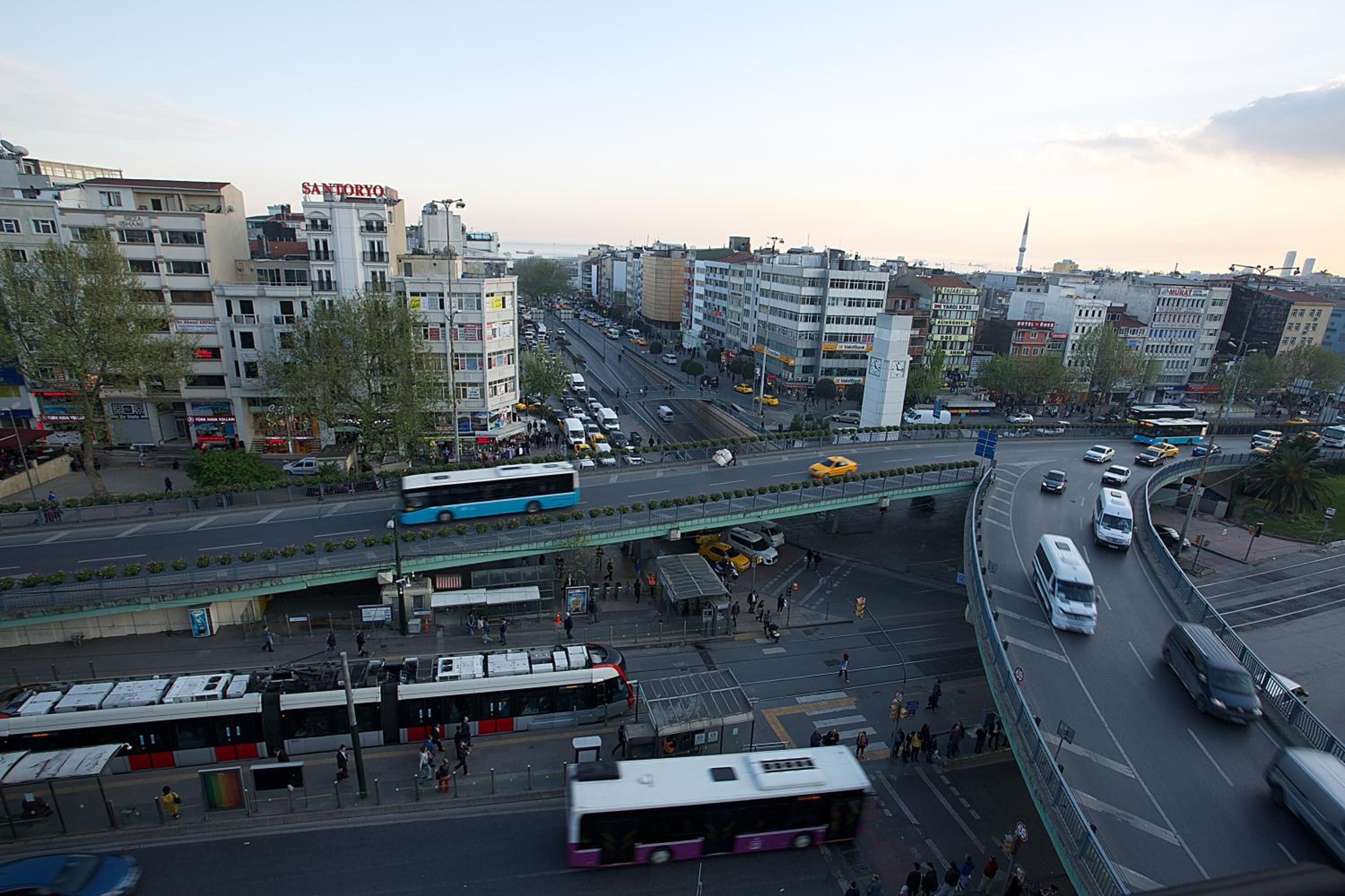 A busy urban street with multiple lanes of traffic, including buses and cars.