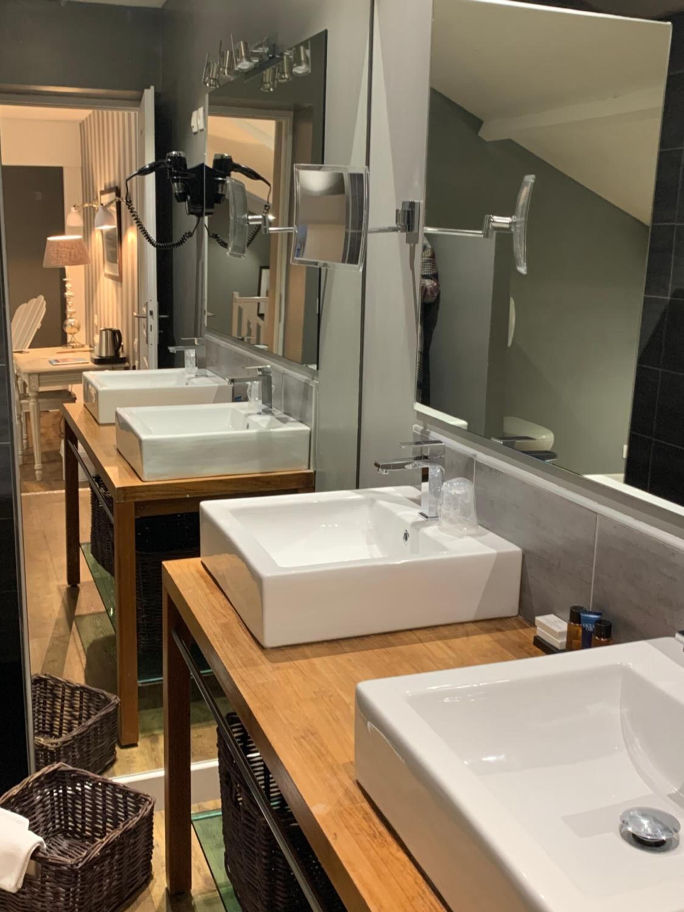Une salle de bain moderne avec deux lavabos, un grand miroir et un espace douche.