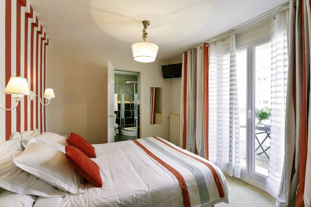 A hotel room with a bed, a TV, and a bathroom visible through an open door.