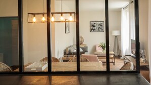 Una sala de estar moderna con una mesa de madera, sillas de mimbre, un sofá y una lámpara colgante.