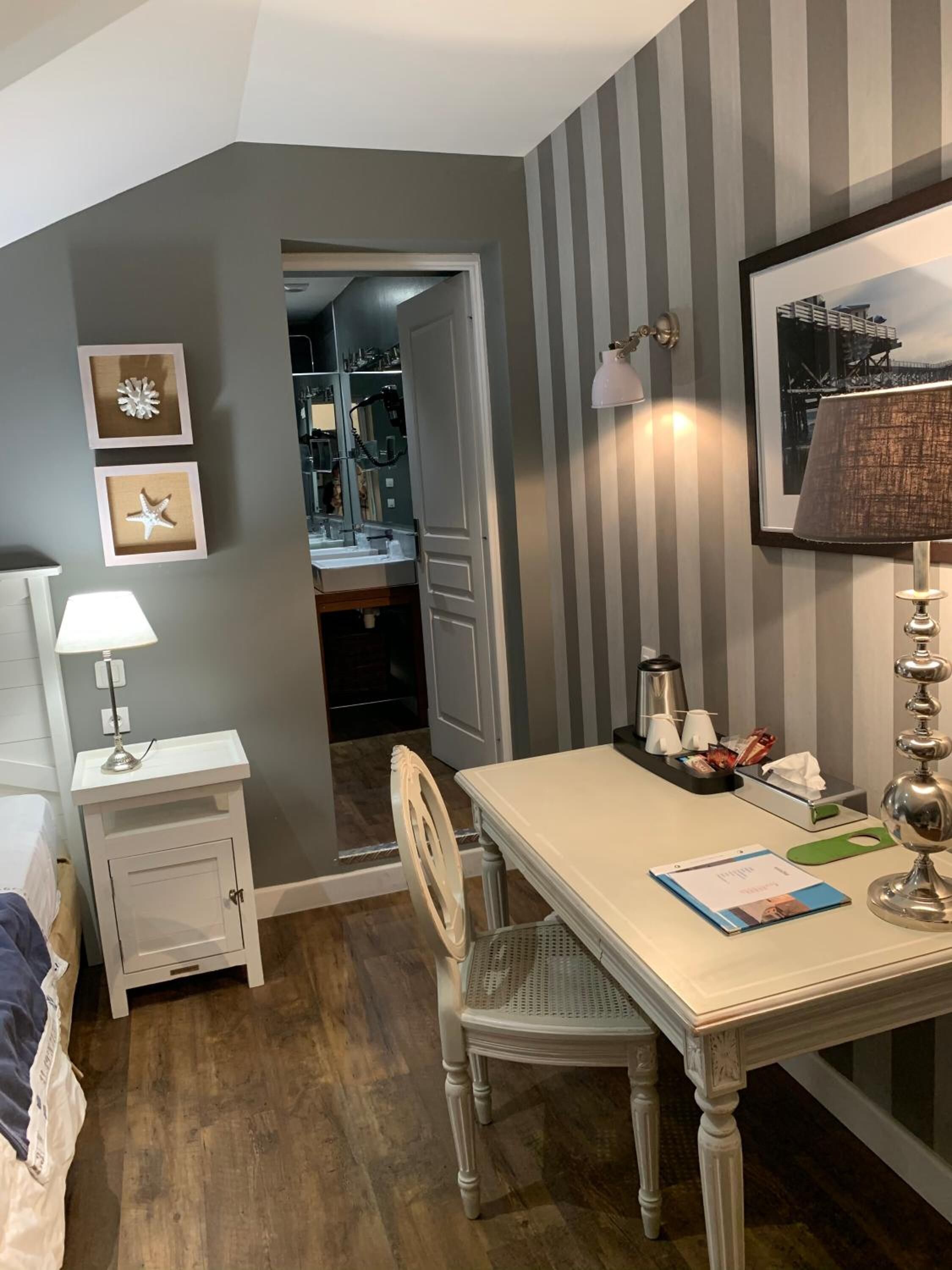 Een kamer met een eettafel, stoelen, een lamp, een kast en een lijst met een afbeelding aan de muur.