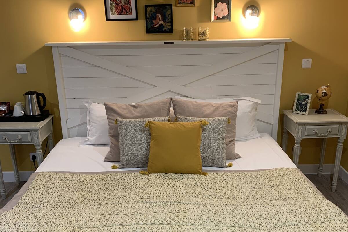 A neatly made bed with a patterned bedspread, a white headboard, and multiple pillows.