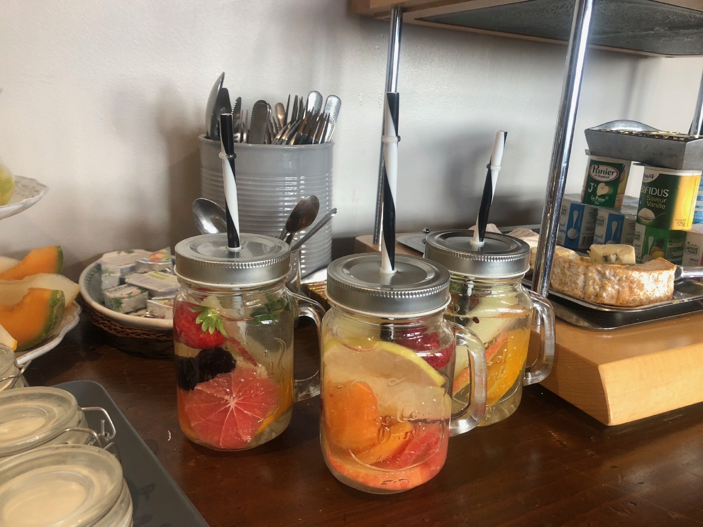 Un buffet de petit-déjeuner comprenant des boissons aromatisées aux fruits, des ustensiles et des produits laitiers.