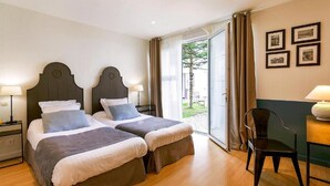 Habitación doble con dos camas, una silla, una mesa y ventana con cortinas.