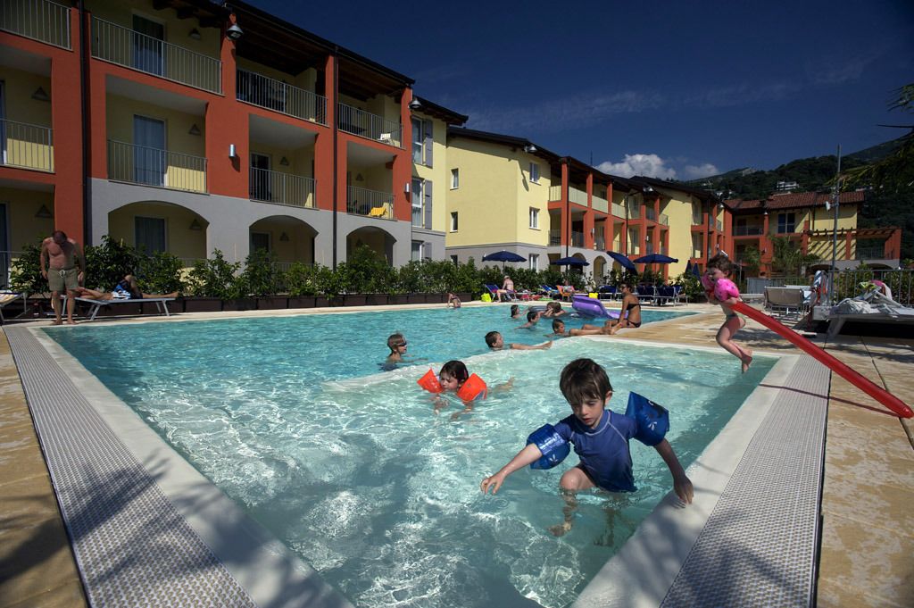 Ein Poolbereich mit mehreren Gebäudebereichen im Hintergrund.
