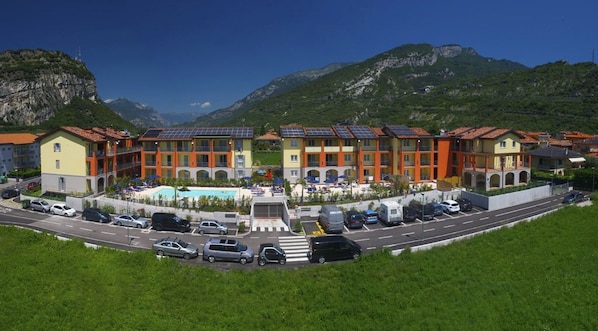 A hotel with multiple buildings, a swimming pool, and a parking area.