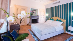 A bedroom with a bed, a nightstand, a chair, a fireplace, and a wall with vertical stripes. - B&B Maiurè (Maiori)