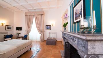 Habitación de hotel con cama, chimenea, una pequeña mesa con un jarrón de flores y vista a la ciudad por la ventana.