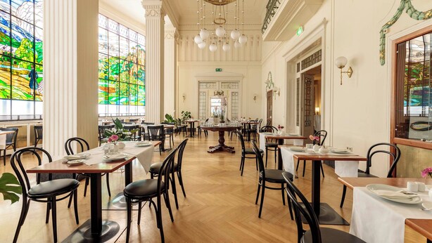 Un comedor espacioso con techos altos, ventanas amplias y elegantes candelabros.