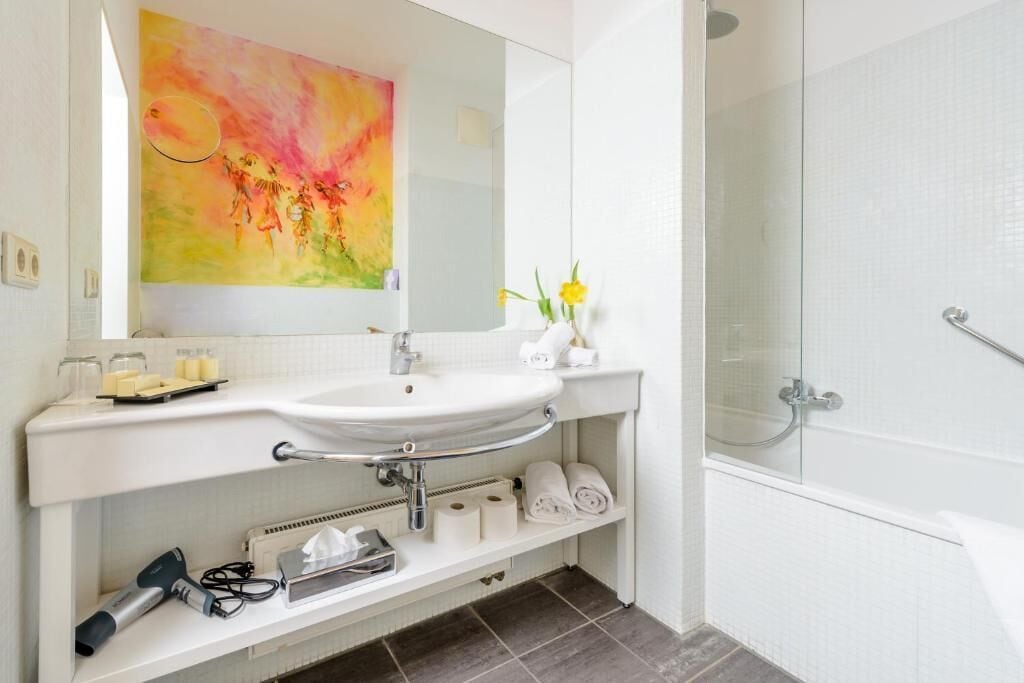 A modern bathroom with a white sink, a glass shower enclosure, and a large mirror above the sink.