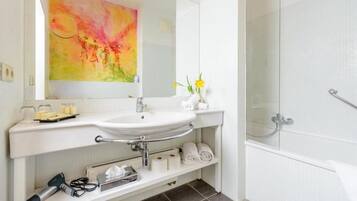 A modern bathroom with a white sink, a glass shower enclosure, and a large mirror above the sink.