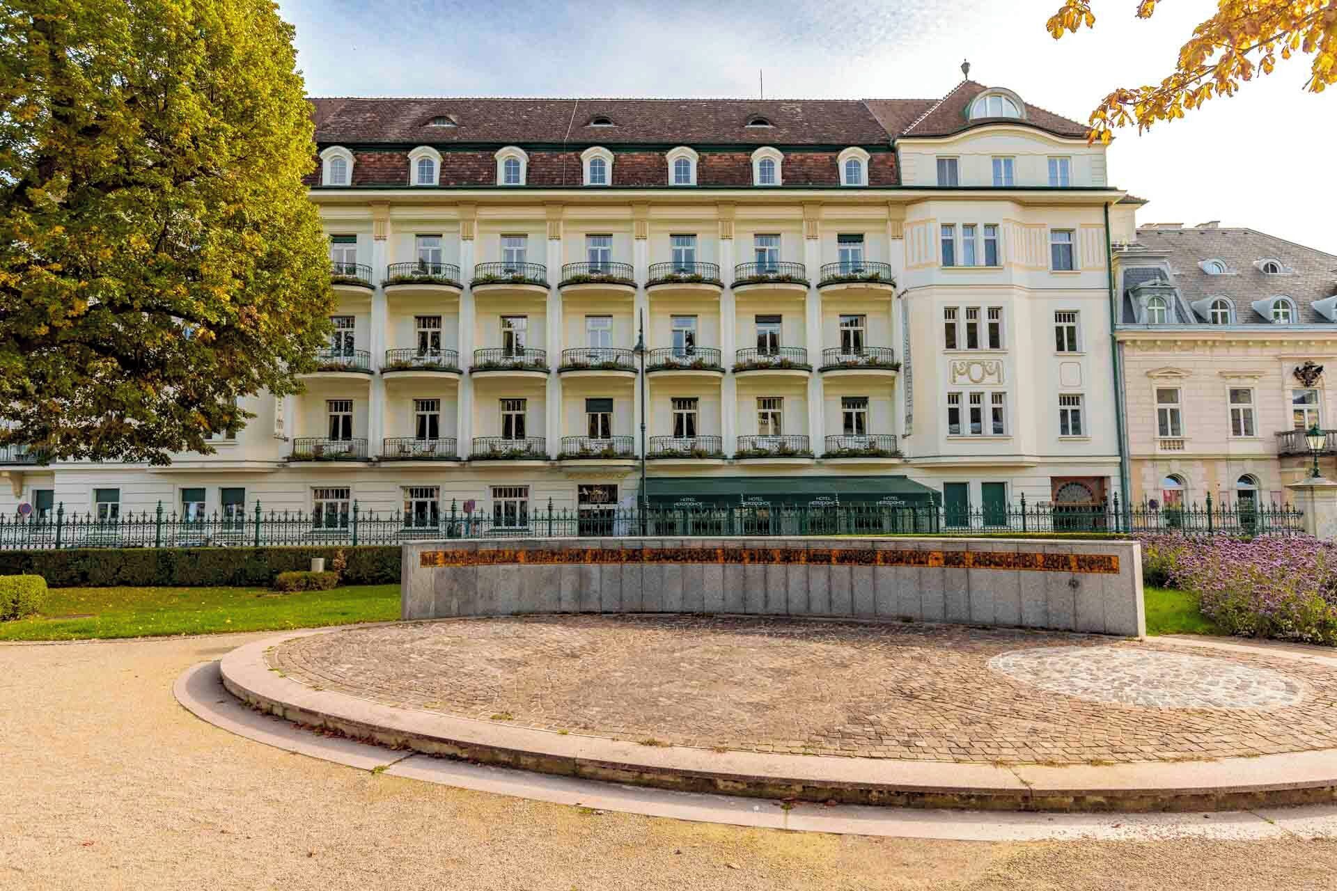 A multi-story hotel with a symmetrical facade, balconies, and a central courtyard.