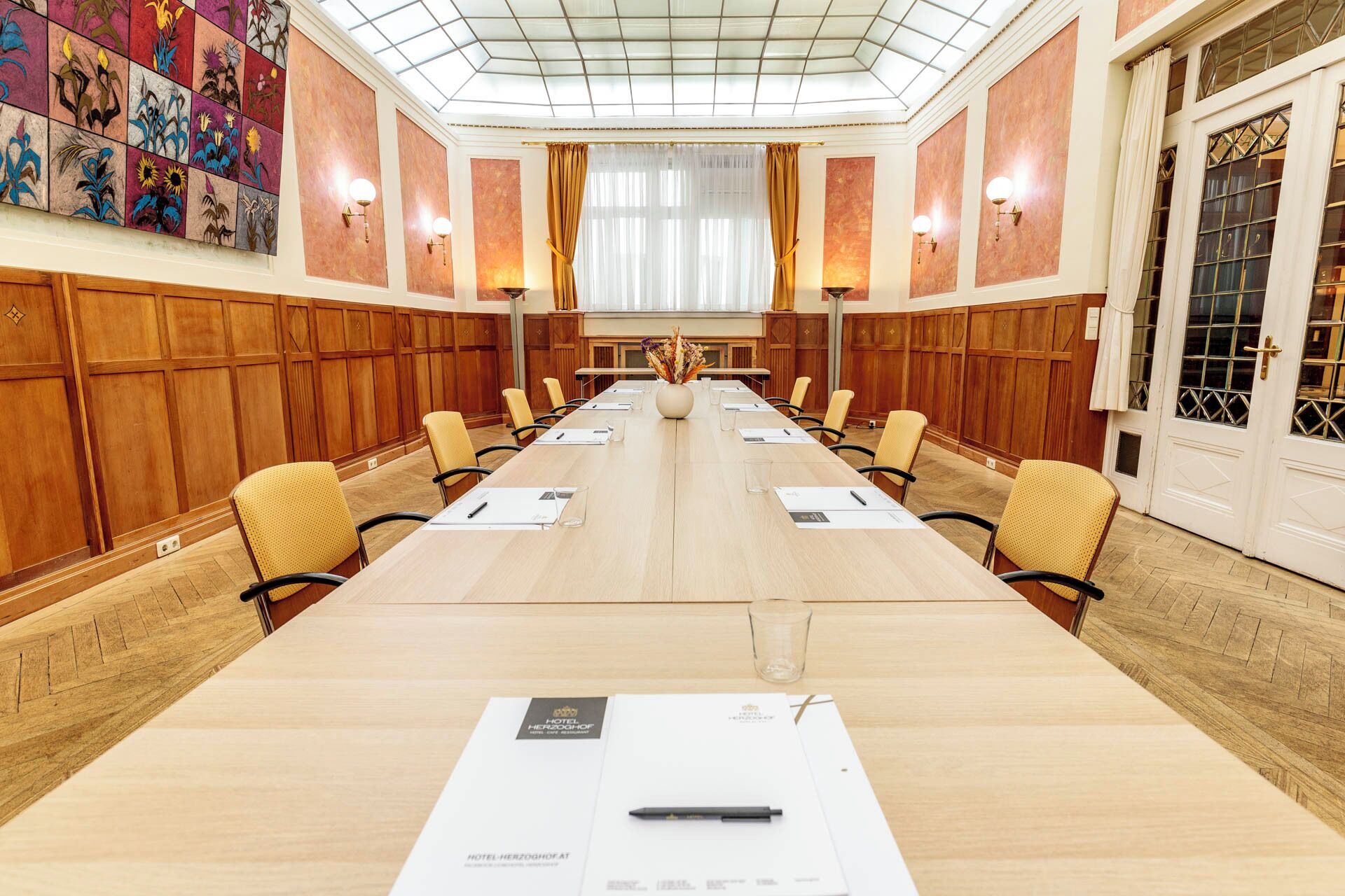 Ein Konferenzraum mit langem Tisch, Stühlen und einer dekorativen Wand.