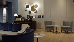A modern lobby with a reception desk, seating area, and decorative wall art. - GKK Exclusive Private Suite (Rome)