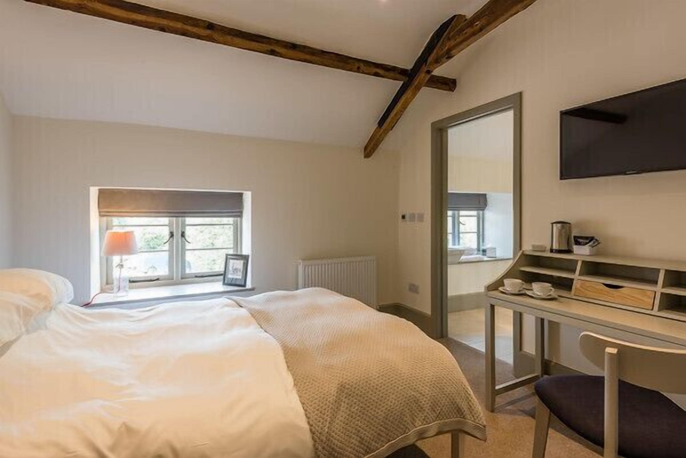 Ein Schlafzimmer mit einem Bett, einem Schreibtisch, einem Stuhl, einem Fernseher und einem Fenster.