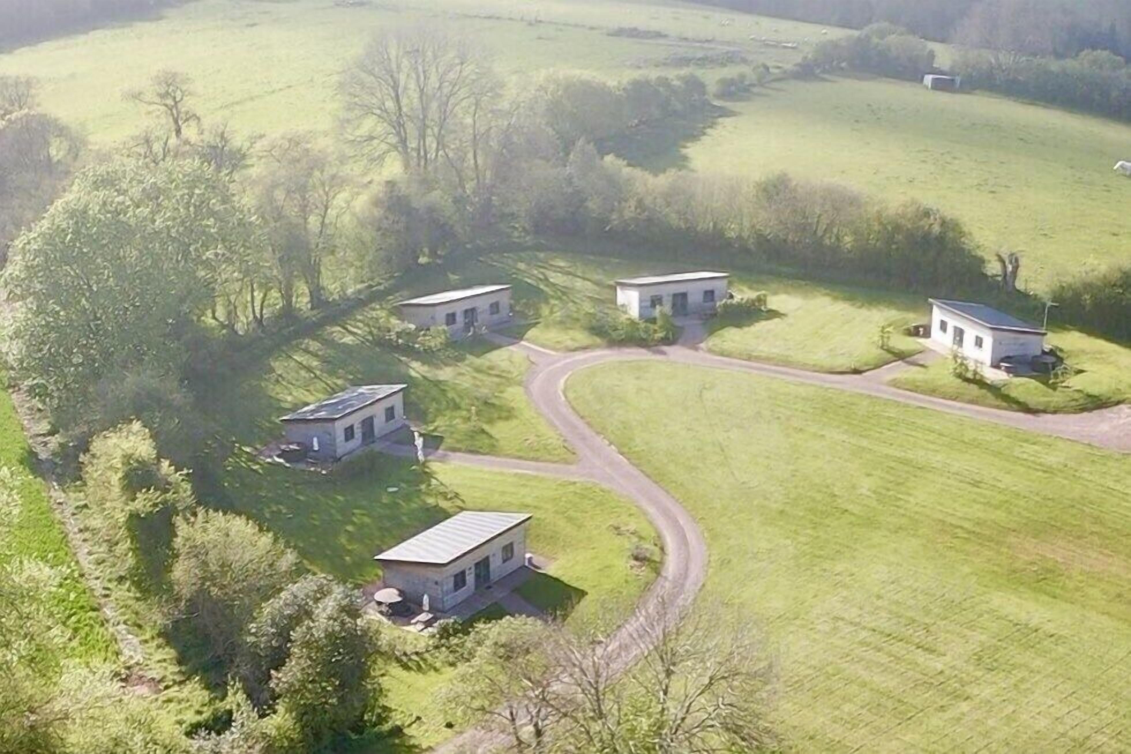A rural property with four detached houses, a winding road, and surrounding greenery.
