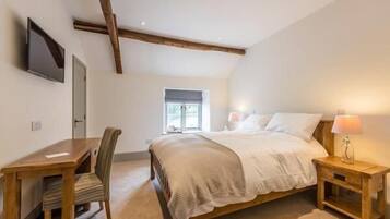 A bedroom with a bed, bedside tables, a desk, a chair, and a television on the wall.