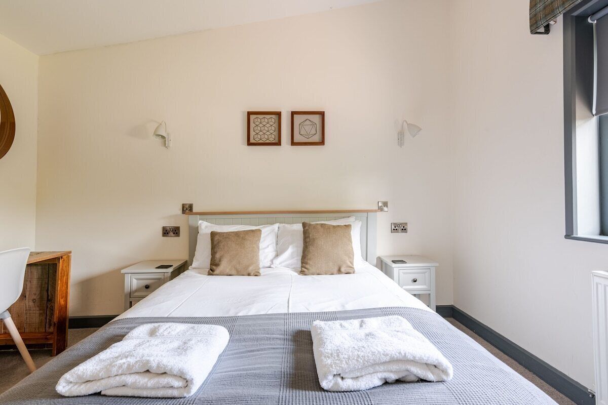 Ein Hotelzimmer mit einem Bett, zwei Nachttischen, einem Beistelltisch, einem Sessel und zwei Wandleuchten.