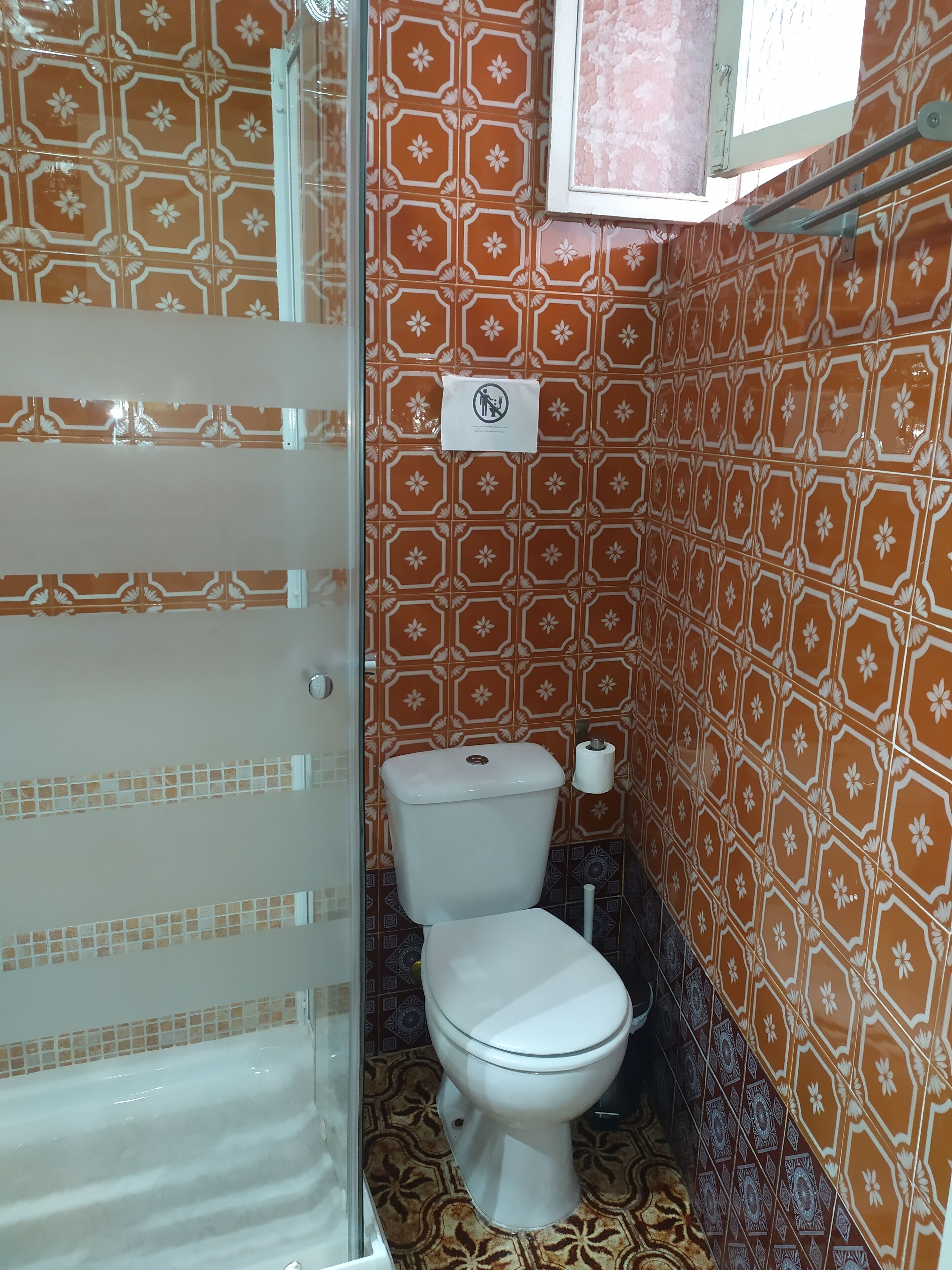 A bathroom with a toilet, a paper towel dispenser, and a shower area.