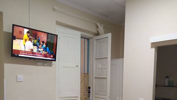 Una habitación con cama, escritorio, silla, televisor y baño.