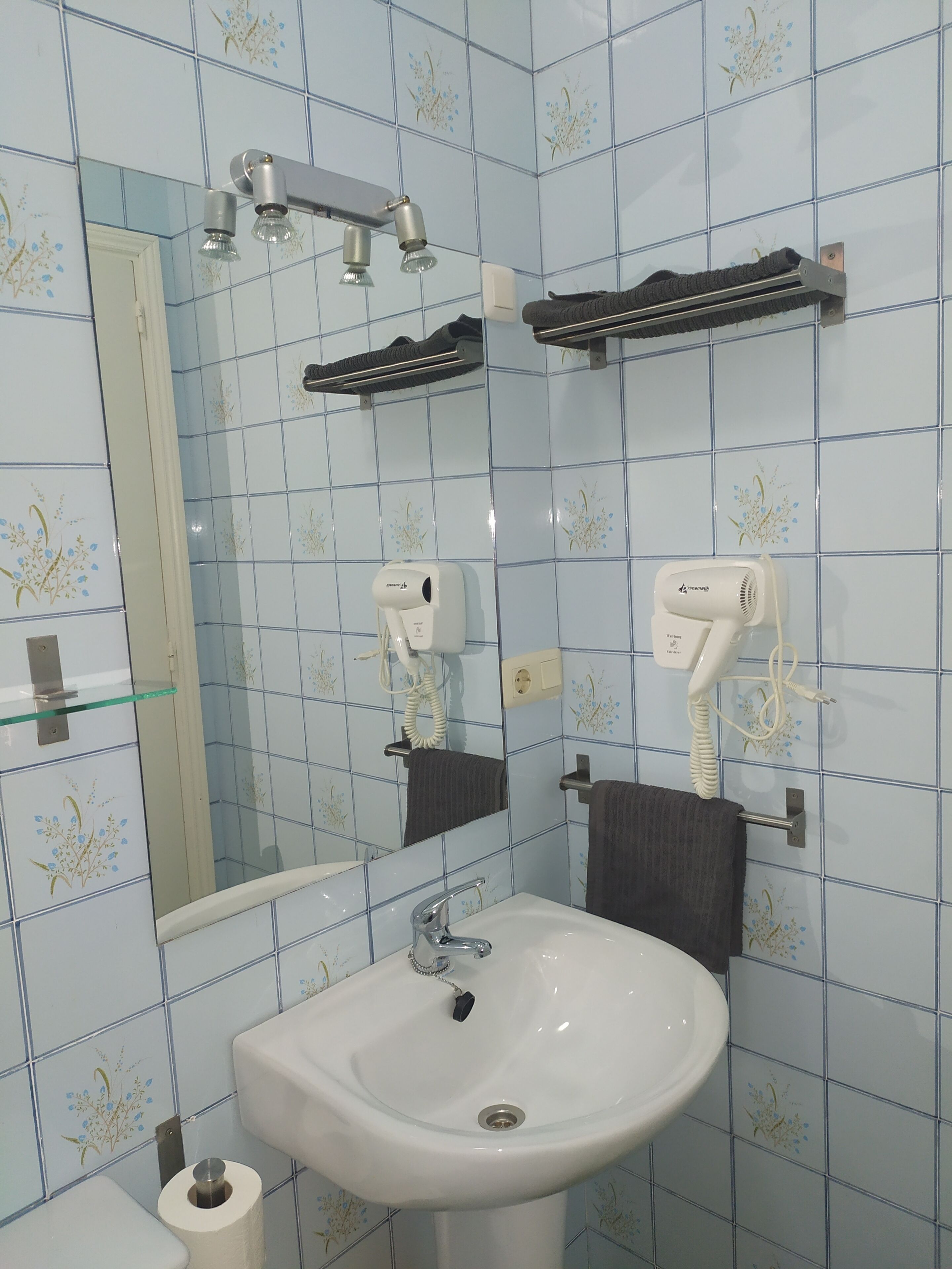 Ein Badezimmer mit Waschbecken, Spiegel, Handtuchhalter und Föhn.
