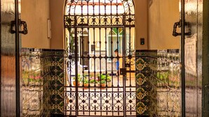 Un pasillo con una reja de hierro forjado que da a un patio. Las paredes están cubiertas de azulejos con un diseño decorativo.