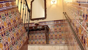Una escalera con paredes de azulejos ornamentales y barandilla de madera.
