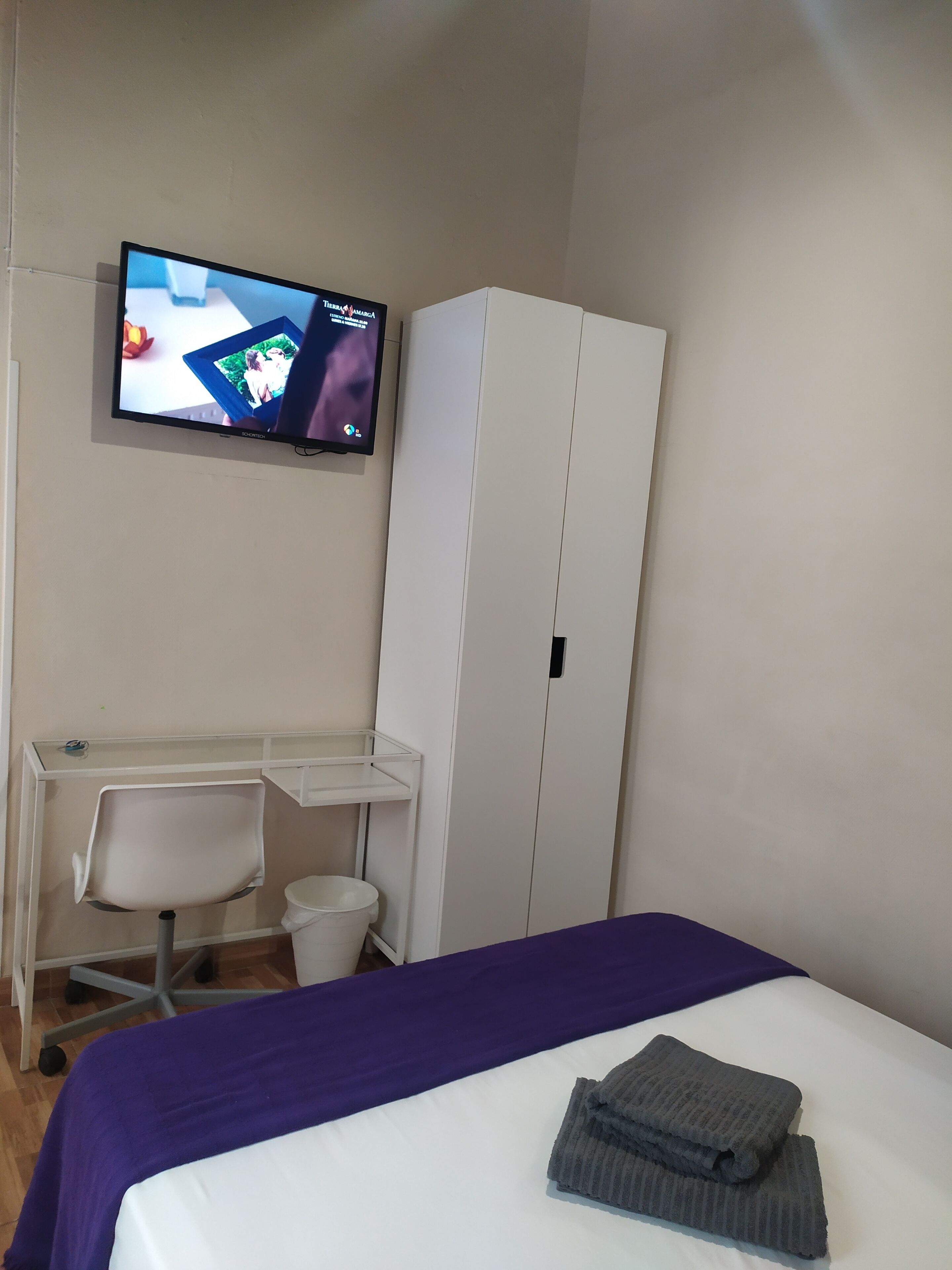 Une chambre d’hôtel équipée d’un lit, d’un bureau, d’une chaise, d’une télévision et d’une armoire.