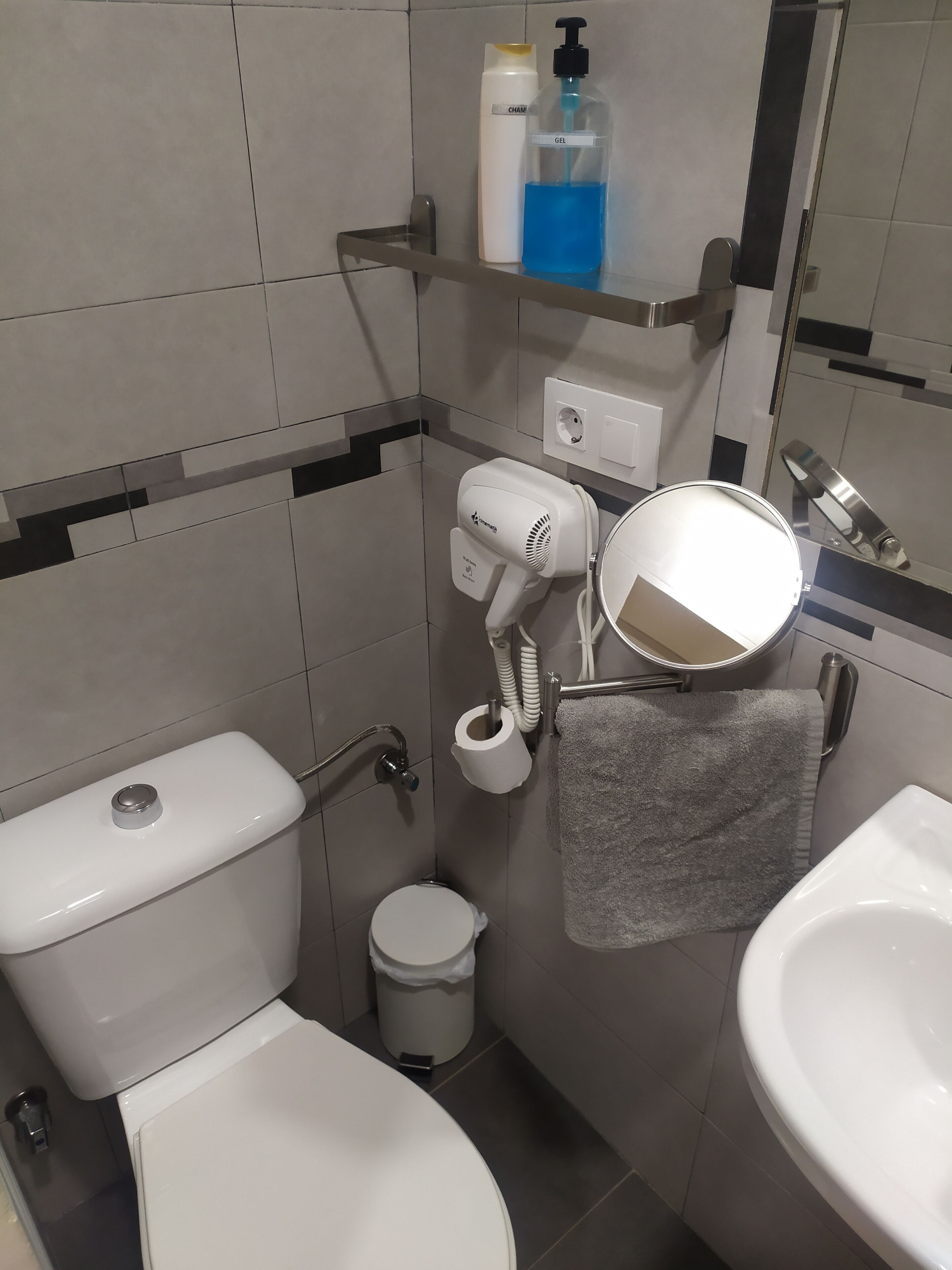 Un bagno compatto con il water, un bidet, un lavandino e uno specchio.
