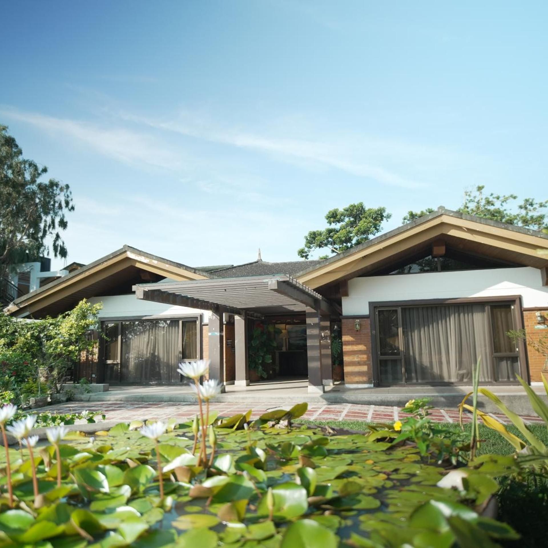 A modern two-story house with a covered patio, a garage, and a garden with water lilies.