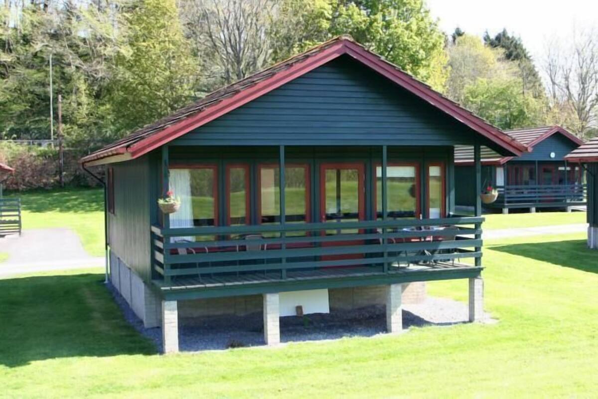 A small, single-story building with a green roof and a balcony.
