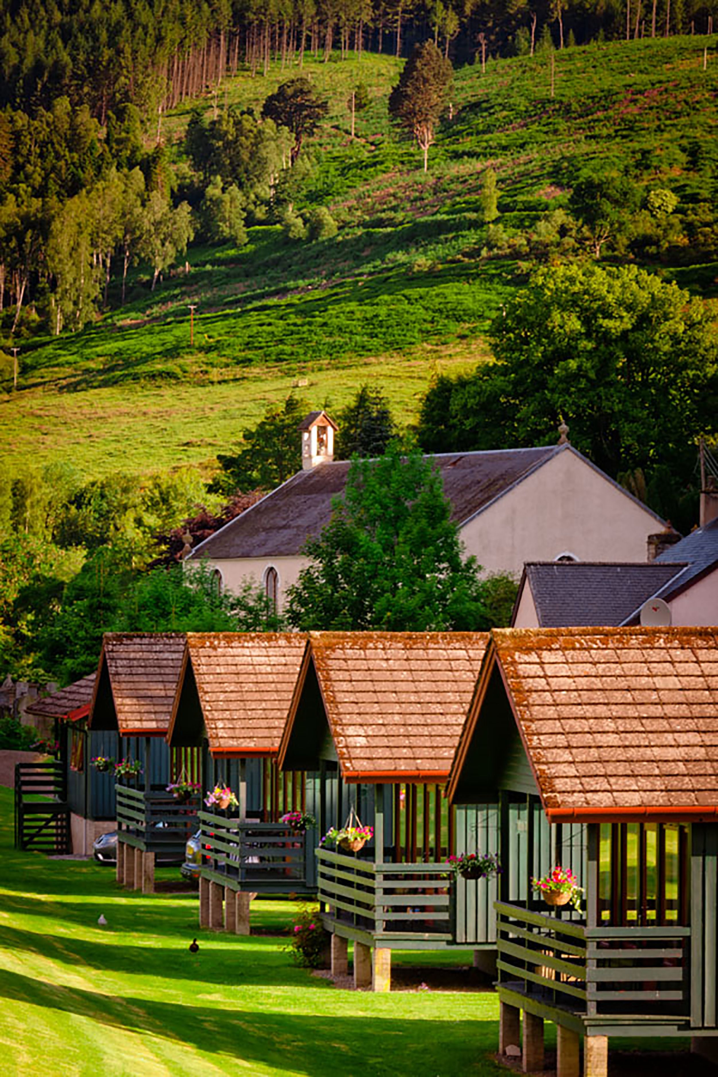 A row of wooden chalets with sloped roofs, each with a balcony and potted plants.